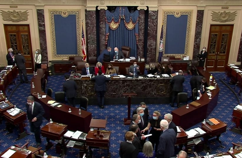 US Senate Minority Leader Mitch McConnell (R-KY) huddles on the Senate floor with Senator Kyrsten Sinema (D-AZ), Senator John Barrasso (R-WY), Senator John Hoeven (R-ND), Senator Dan Sullivan (R-AK), Senator James Lankford (R-OK), Senator Joni Ernst (R-IA) and Senator John Cornyn (R-TX) and others (photo credit: REUTERS)