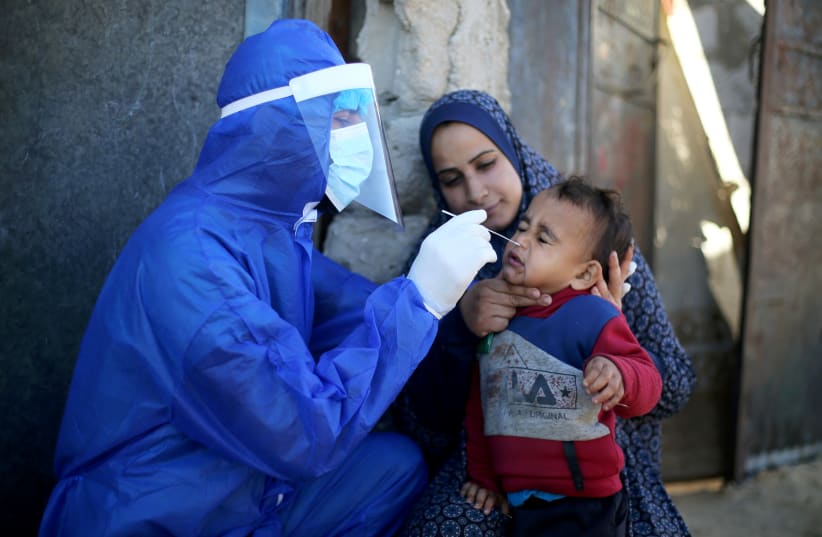  Palestinian medical worker collects a swab sample from a boy to be tested for the coronavirus disease (COVID-19), in the southern Gaza Strip January 14, 2021. (photo credit: REUTERS)
