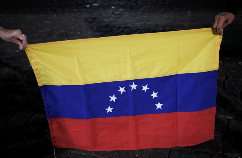 Venezuelans hold a Venezuelan flag as they take part in a protest in support of Venezuelan opposition leader Juan Guaido in Sao Paulo, Brazil, April 30, 2019. (photo credit: REUTERS/NACHO DOCE)