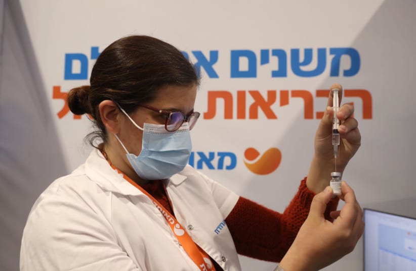 A medical worker is seen filling up a coronavirus vaccine dose at a Meuhedet vaccination center in Jerusalem, on February 16, 2021. (photo credit: MARC ISRAEL SELLEM/THE JERUSALEM POST)