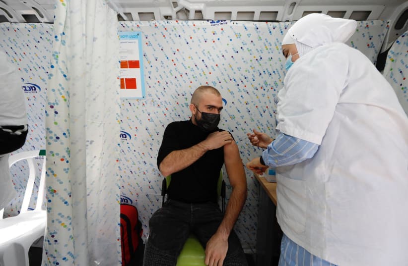 A resident of Tel-Aviv gets COVID-19 vaccine shot on Tuesday February 16 2021 (photo credit: GUY YECHIELI)
