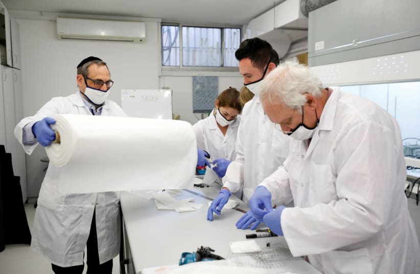 Employees of Israel's Sonovia Ltd, makers of washable and reusable antiviral masks, which the company says can help stop the spread of the coronavirus disease (COVID-19), work at their laboratory in Ramat Gan, Israel May 17, 2020.  (photo credit: AMIR COHEN/REUTERS)