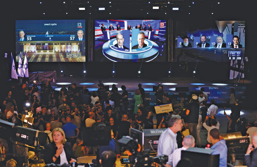 THE RESULTS of the exit polls on channels 11, 12 and 13 are shown on large screens at Blue and White Party headquarters following the September 2019 election. (photo credit: AMIR COHEN/REUTERS)