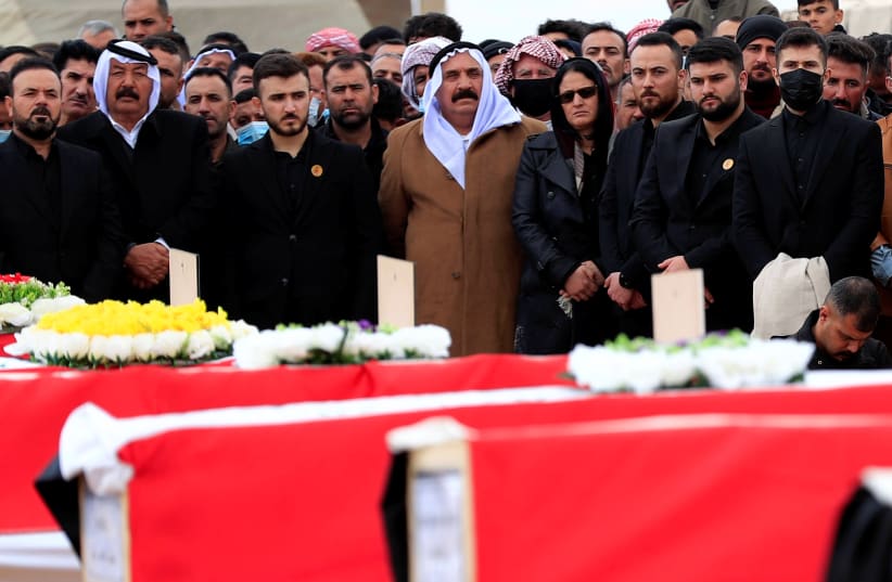 Mourners stand next to the coffins with the remains of people from the Yazidi minority, who were killed by Islamic State militants, after they were exhumed from a mass grave, to bury them in Kojo, Iraq February 6, 2021.  (photo credit: REUTERS/THAIER AL-SUDANI)