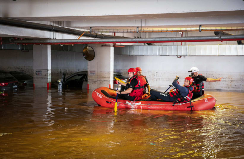 Israeli firefighters sit in a rescue boat as they search for people at a parking lot that was flooded following heavy rainfall in Ness Ziona, November 21, 2020. (photo credit: YOSSI ALONI/FLASH90)