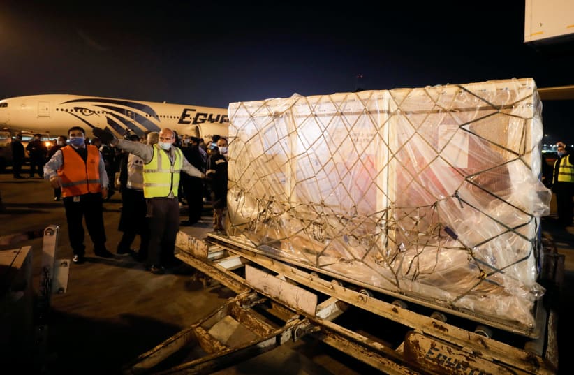 Workers offload pallets containing coronavirus disease (COVID-19) vaccine "Sinopharm" doses as they arrive from China at Cairo International Airport amid the coronavirus disease (COVID-19) pandemic in Cairo, Egypt February 23, 2021 (photo credit: MOHAMED ABD EL GHANY/REUTERS)