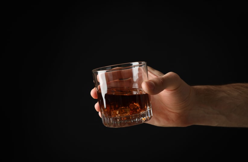A man holds a glass of scotch. (photo credit: ISTOCK)