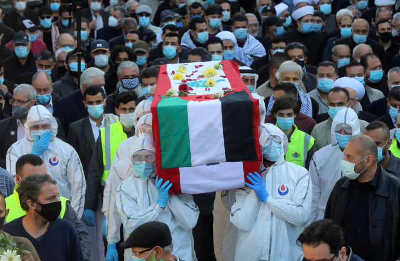 People wearing protective suits carry the coffin of Anis Naccache, a former pro-Palestinian militant, during his funeral in Beirut suburbs, Lebanon February 24, 2021. (photo credit: MOHAMED AZAKIR / REUTERS)