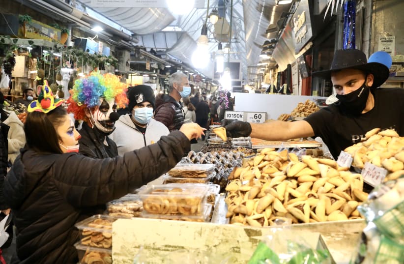 Israelis in Purim costume buy hamentashen from a Mahaneh Yehuda seller. (photo credit: MARC ISRAEL SELLEM/THE JERUSALEM POST)