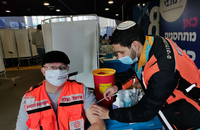 United Hatzalah volunteer vaccinating another in Jerusalem in December (photo credit: UNITED HATZALAH‏)