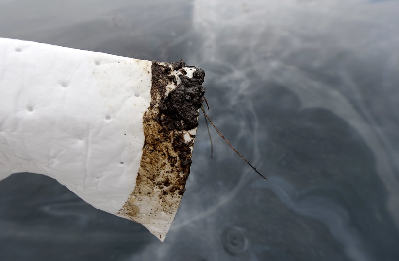 An absorbent is used to show oil slick in the waters off Refugio State Beach on the Californian coast in Goleta, California, United States, May 21, 2015. An oil pipeline that burst along the California coast, fouling pristine beach and stretch of ocean near Santa Barbara, is believed to have spilled (photo credit: KEVORK DJANSEZIAN/REUTERS)