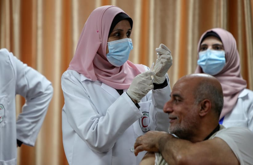 A health worker prepares to vaccinate former Palestinian health minister Jawad Tibi against the coronavirus disease (COVID-19) vaccine in Gaza City February 22, 2021. (photo credit: REUTERS)