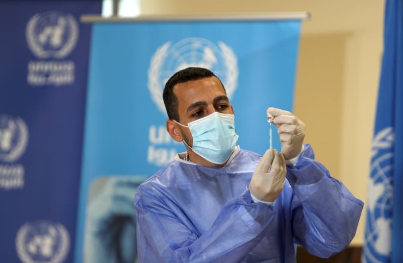 A Palestinian health worker prepares to vaccinate Matthias Schmale, UNRWA's Gaza director, against the coronavirus disease (COVID-19), in Gaza City February 24, 2021.  (photo credit: REUTERS)