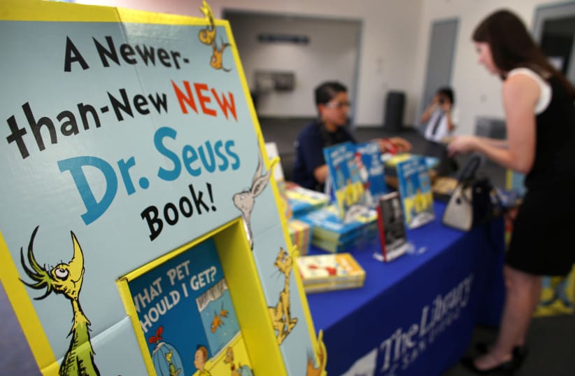 A woman purchases the new release of the Dr. Seuss book "What Pet Should I Get?" after waiting in line at the University of California San Diego's Geisel Library in San Diego, California July 28, 2015. (photo credit: MIKE BLAKE/ REUTERS)