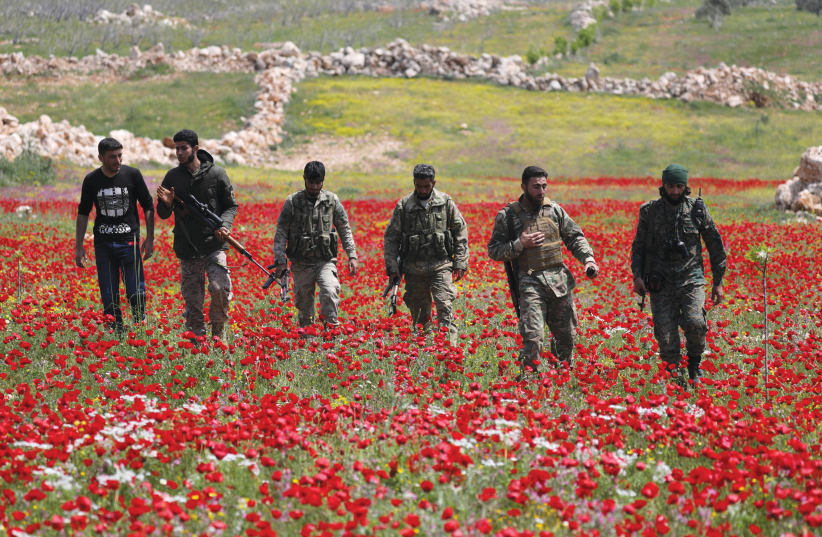 TURKISH-BACKED FIGHTERS walk through the southern countryside of Syria’s Idlib Province in April. (photo credit: KHALIL ASHAWI / REUTERS)