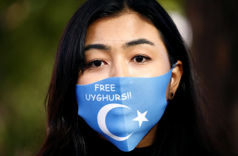 A woman wearing a mask with a Uyghur flag takes part in a rally during China's Foreign Minister Wang Yi's visit in Berlin, Germany September 1, 2020.  (photo credit: REUTERS/MICHELE TANTUSSI)