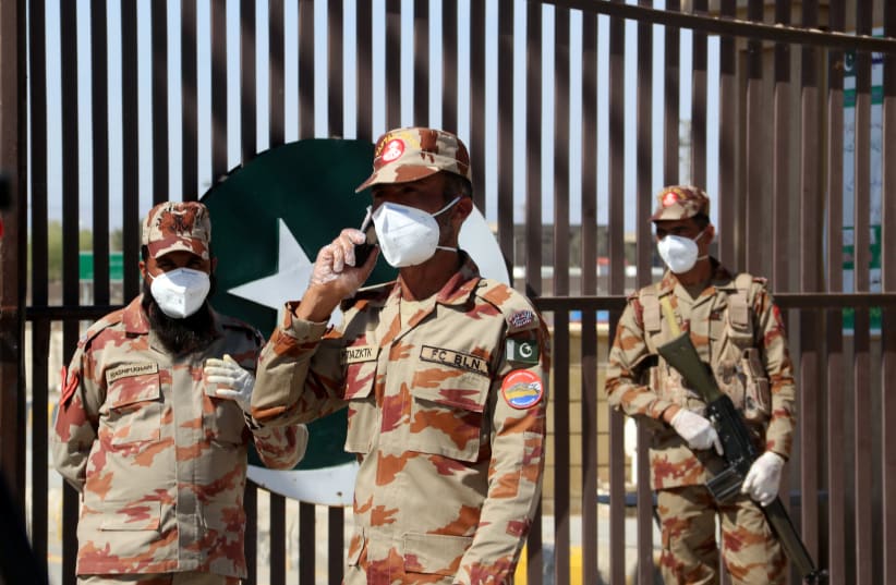 Paramilitary soldiers wear face masks as they stand in front of a closed gate of Pakistan's border post, after Pakistan sealed its border with Iran as a preventive measure following the coronavirus outbreak, at the border post in Taftan, Pakistan February 25, 2020. (photo credit: REUTERS/NASEER AHMED)