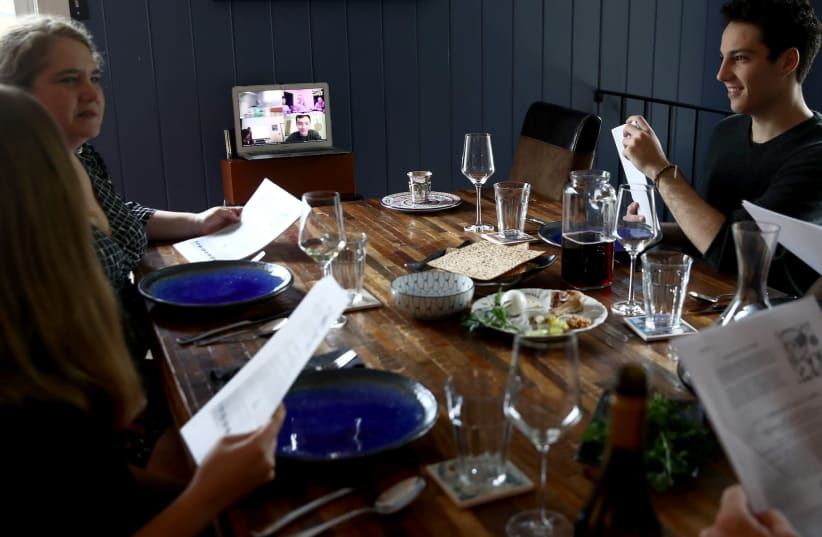A family celebrates the Passover Seder with other family members joining via Zoom, April 8, 2020. (photo credit: EZRA SHAW/GETTY IMAGES)