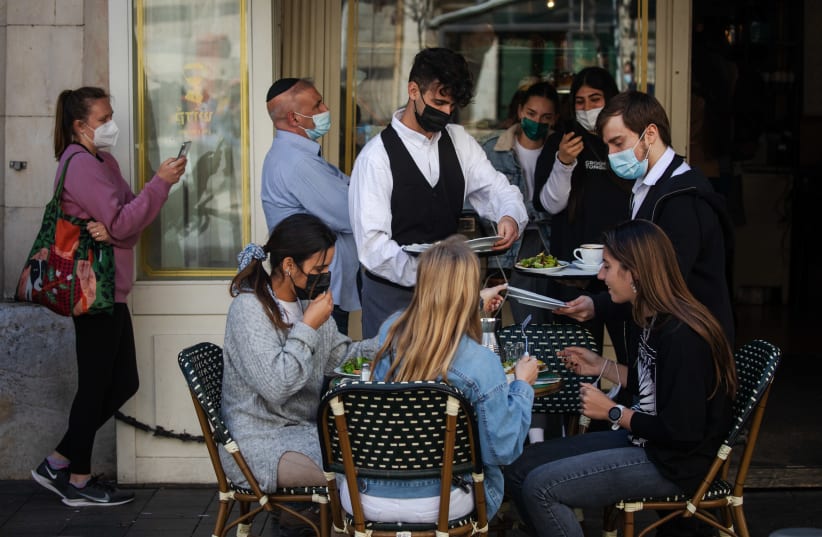 Customers sit at a cafe  in Jerusalem after it was reopened on March 7, 2021 (photo credit: OLIVIER FITOUSSI/FLASH90)