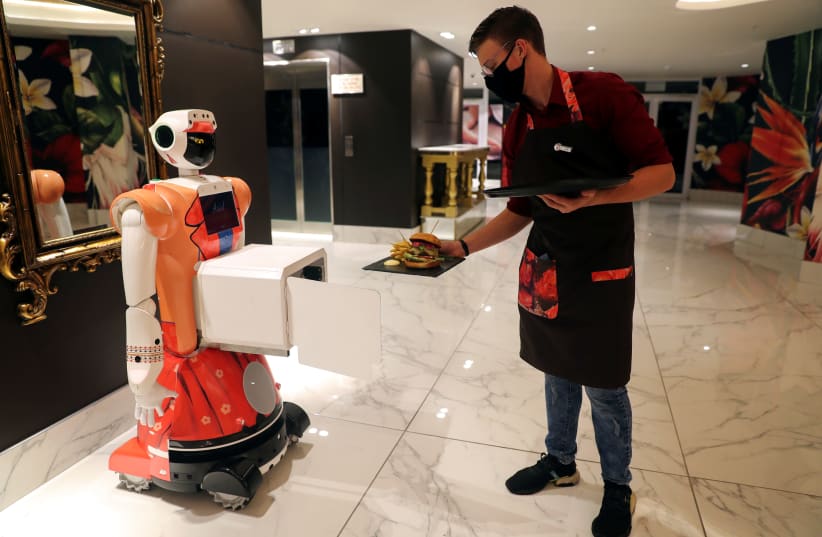 PLACING FOOD in a box attached to AI-powered robot Ariel for delivery to a guest at Johannesburg’s Hotel Sky last month. The novel mirrors character development between an Artificial Friend and humans (photo credit: SUMAYA HISHAM/REUTERS)