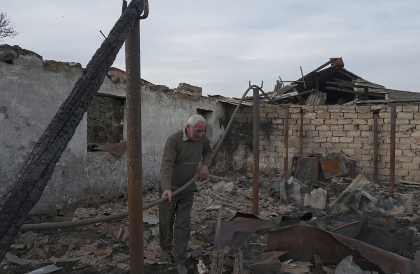 Local resident Lenser Gabrielyan, 65, stands on the ruins of his farm that was destroyed by shelling near the village of Taghavard in the region of Nagorno-Karabakh, January 16, 2021. Following the military conflict over Nagorno-Karabakh and a further signing of a ceasefire deal, the village was div (photo credit: REUTERS/ARTEM MIKRYUKOV)