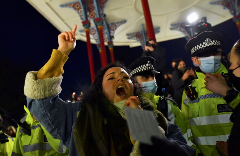 A woman shouts near police members as people gather at a memorial site at the Clapham Common Bandstand, following the kidnap and murder of Sarah Everard, in London, Britain, March 13, 2021. (photo credit: REUTERS)