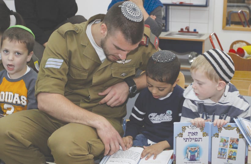 A SOLDIER in an IDF conversion course interacts with children praying at their kindergarten in 2013. (photo credit: GERSHON ELINSON/FLASH90)