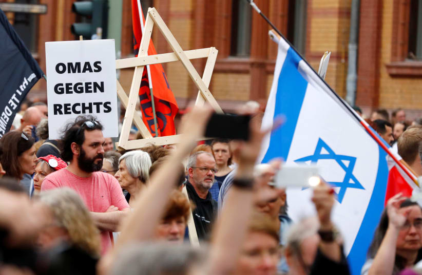 A man carries a wooden Star of David as people attend a demonstration themed with the slogan "#unteilbar" (indivisible) to protest against antisemitism, racism and nationalism in Berlin, Germany, October 13, 2019. (photo credit: REUTERS/HANNIBAL HANSCHKE)