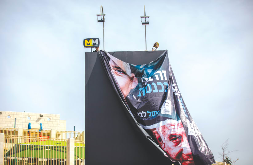 WORKERS HANG a large election campaign poster in Jerusalem last week. (photo credit: YONATAN SINDEL/FLASH90)