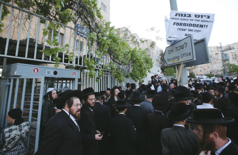 HUNDREDS OF haredi protesters gather outside the IDF recruitment office in Jerusalem’s Mekor Baruch neighborhood to protest IDF induction, in 2018. (photo credit: MARC ISRAEL SELLEM/THE JERUSALEM POST)