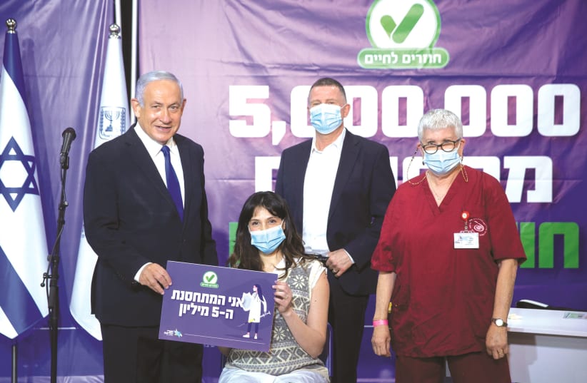 PRIME MINISTER Benjamin Netanyahu and Health Minister Yuli Edelstein are seen during a visit to a Leumit Health Care Services COVID-19 vaccination center in Tel Aviv, with the five millionth Israeli who received a vaccination, last week.  (photo credit: MIRIAM ALSTER/FLASH90)