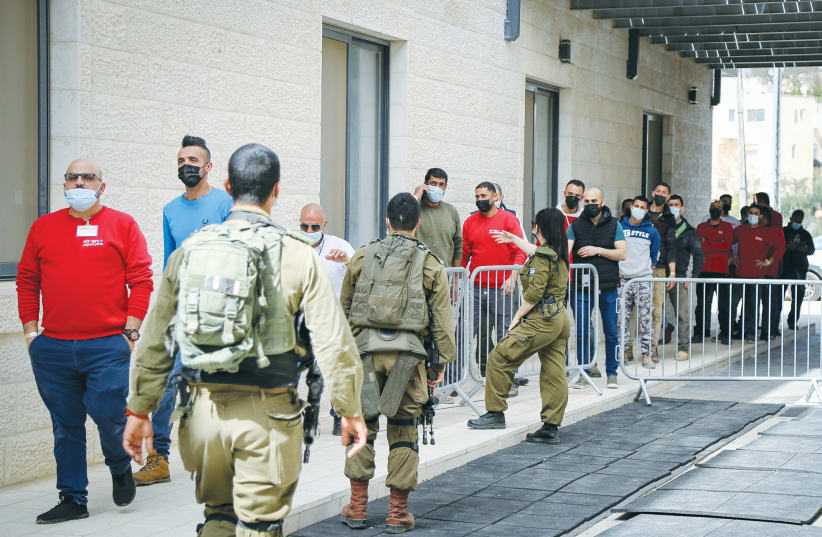 PALESTINIANS WHO work in Gush Etzion wait in line for a COVID-19 vaccine shot in Efrat last week. (photo credit: GERSHON ELINSON/FLASH90)