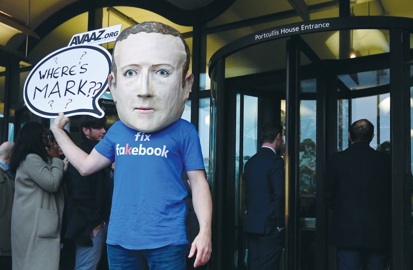 A campaigner from a political pressure group wears a mask of Facebook founder and CEO Mark Zuckerberg in London in November 2018.  (photo credit: TOBY MELVILLE/REUTERS)
