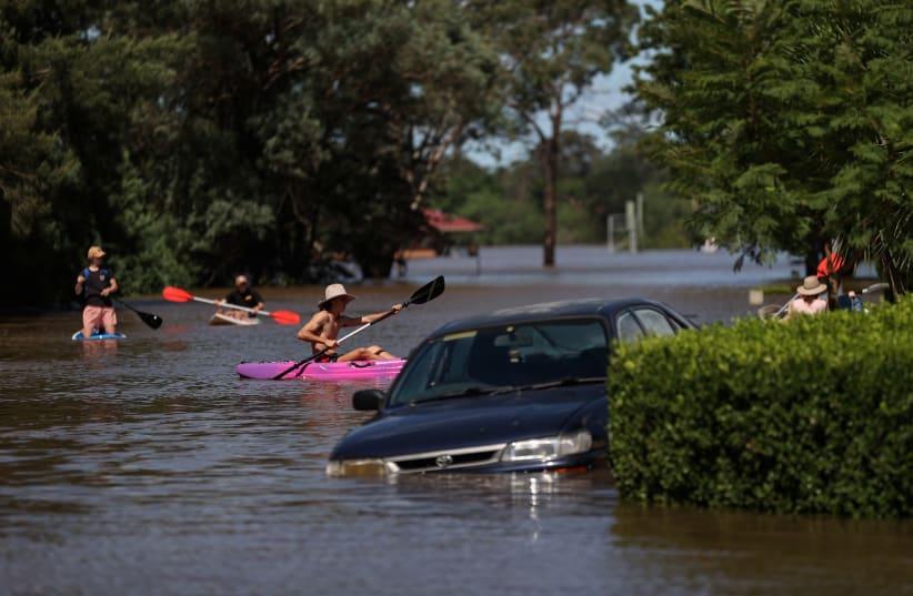 People using kayaks and paddle boards navigate a residential neighbourhood inundated with floodwaters as severe flooding affects the suburb of McGraths Hill in Sydney, Australia, March 24, 2021. (photo credit: LOREN ELLIOTT/REUTERS)