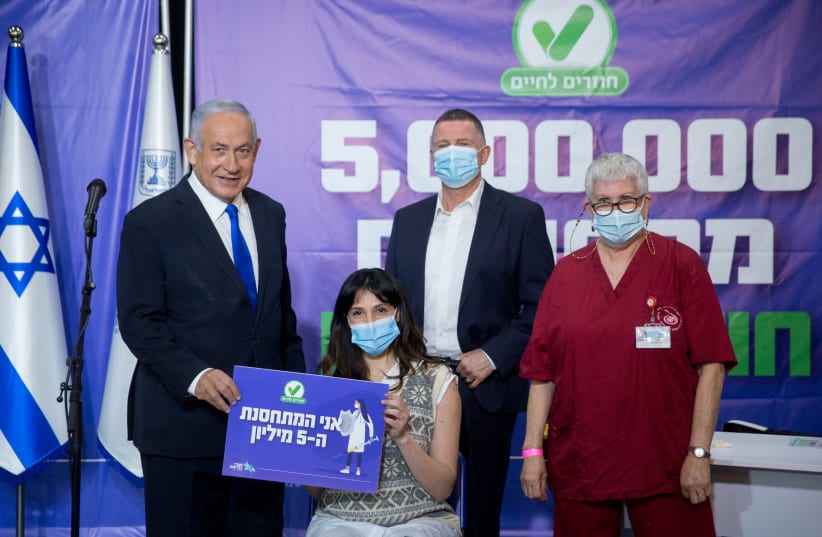 Prime Minister Benjamin Netanyahu and Health Minister Yuli Edelstein pose for a photograph with Janet Lavi-Azulay, 34, the 5 millionth Israeli to get the Pfize vaccine, in Tel Aviv on March 8 (photo credit: MIRIAM ALSTER/POOL/REUTERS)