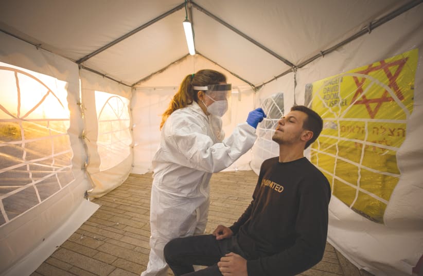 A MAGEN DAVID ADOM medical worker tests people for coronavirus at a mobile site in Jerusalem. (photo credit: OLIVIER FITOUSSI/FLASH90)