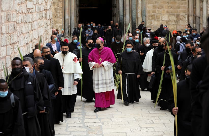 Latin Patriarch of Jerusalem Pierbattista Pizzaballa walks along Christian worshippers and the clergy holding palm fronds during a Palm Sunday procession outside the Church of the Holy Sepulchre in Jerusalem's Old City March 28, 2021. (photo credit: REUTERS/AMMAR AWAD)