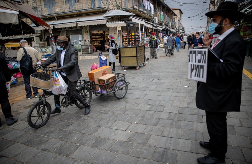 An Ultra orthodox jewish man walks at the Mahane Yehuda market in Jerusalem on March 22, 2021.  (photo credit: YONATAN SINDEL/FLASH 90)