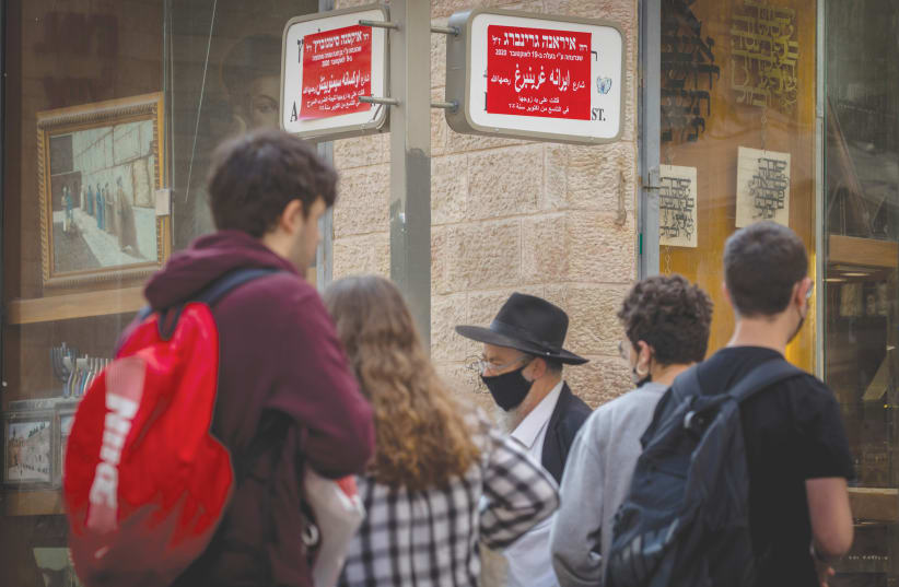 PASSERSBY WALK by signs whose names have been changed to those of women killed in domestic violence in Jerusalem, in November 2020 to mark the Day For Elimination Of Violence Against Women. (photo credit: OLIVIER FITOUSSI/FLASH90)