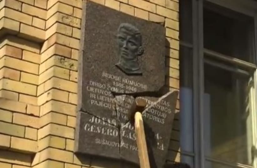 A screenshot of Prof. Dr. Stanislovas Tomas' video in which he destroys a Nazi collaborator's plaque (photo credit: screenshot)