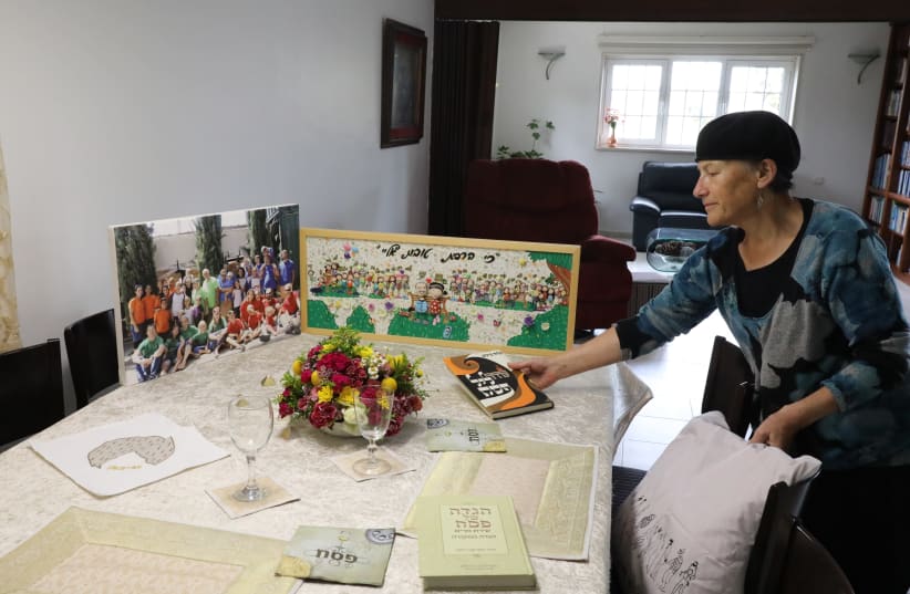 LONELY SEDER: Arranging the 2020 Passover table with pictures of children and grandchildren standing in for the real thing. (photo credit: GERSHON ELINSON/FLASH90)