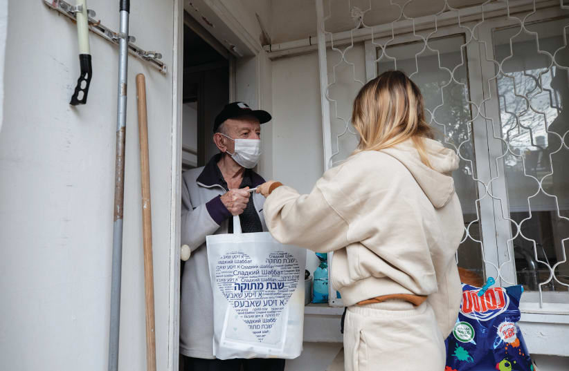 A VOLUNTEER delivers a food package to a Holocaust survivor in Ramat Gan in January. (photo credit: CHEN LEOPOLD/FLASH90)