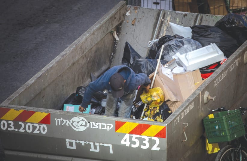 A BOY searches through a garbage container in downtown Jerusalem in December. (photo credit: YONATAN SINDEL/FLASH90)