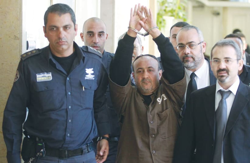 FATAH LEADER Marwan Barghouti is escorted in handcuffs into the Jerusalem Magistrate’s Court in 2012. (photo credit: FLASH90)