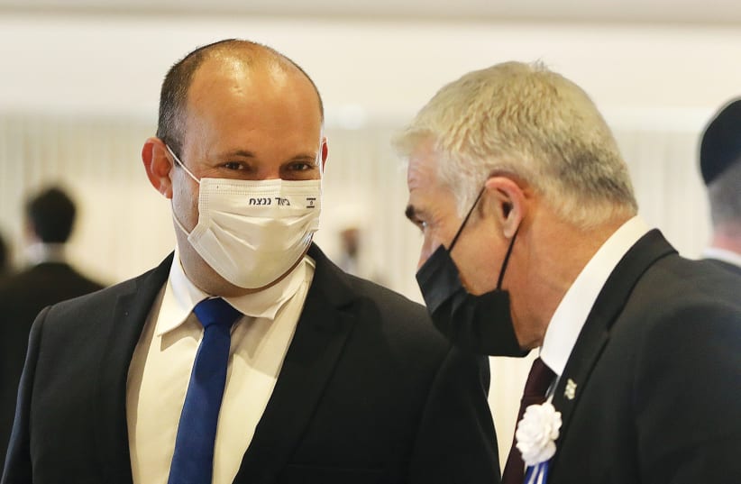 YAMINA LEADER Naftali Bennett (left) talks with Yesh Atid head Yair Lapid at the inauguration of the Knesset on Tuesday. The slogan on Bennett’s mask says, ‘Together we will win.’ (photo credit: MARC ISRAEL SELLEM/THE JERUSALEM POST)