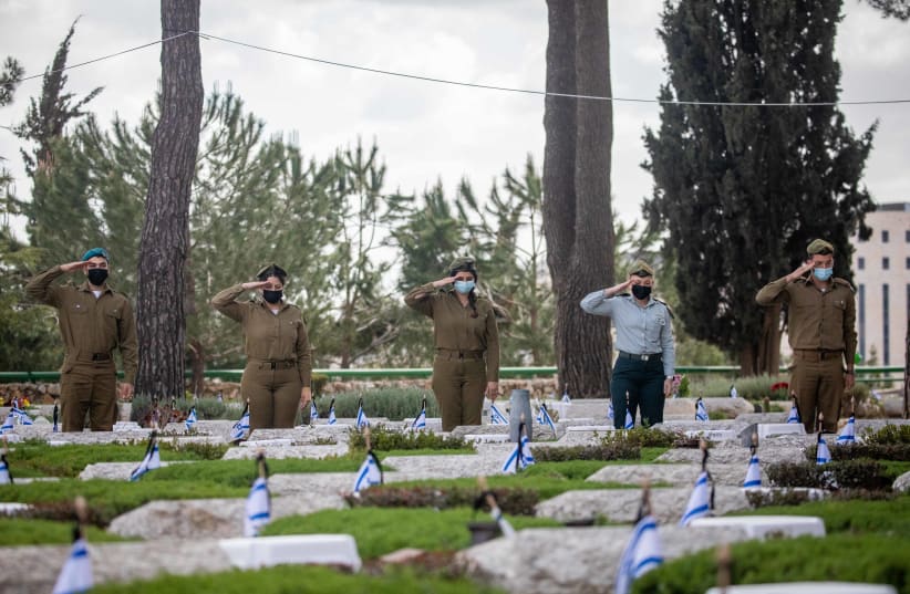 Israeli soldiers place Israeli flags on the graves of fallen soldiers in Mount Herzl Military Cemetery in Jerusalem, on April 11, 2021 (photo credit: YONATAN SINDEL/FLASH90)