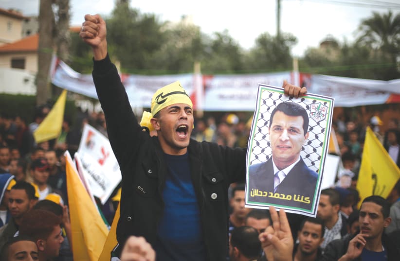A MAN holds a poster of former Gaza Fatah leader Mohammed Dahlan during a protest against PA President Mahmoud Abbas in Gaza City in 2014. (photo credit: REUTERS)
