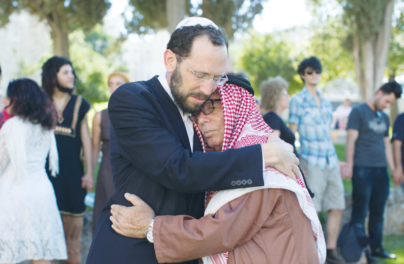 RABBI YAKOV NAGEN of Otniel embraces Haj Ibrahim Ahmad Abu el-Hawa of Jerusalem during an event called The Big Hug, in 2013. (photo credit: SARAH SCHUMAN/ FLASH90)
