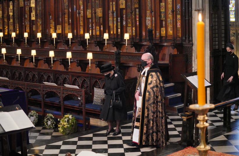Queen Elizabeth is conducted by David Conner, the Dean of Windsor into the Quire of St George's Chapel during the funeral service of Britain's Prince Philip, husband of Queen Elizabeth, who died at the age of 99, in Windsor, Britain, April 17, 2021.  (photo credit: DOMINIC LIPINSKI/REUTERS)