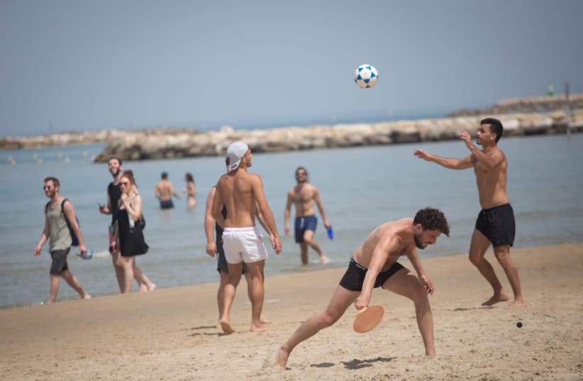 Israelis enjoy the beach on a hot spring day, in Tel Aviv, April 06, 2021 (photo credit: MIRIAM ALSTER/FLASH90)